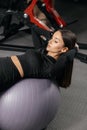 Young beautiful tanned woman doing fitness exercises with a ball