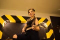 Young beautiful tattooed girl with a guitar, rock singer recording the sound in professional studio on the striped wall Royalty Free Stock Photo