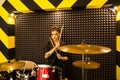 Young beautiful tattooed girl in a leather jacket plays drums in a recording Studio on the bright black and yellow band