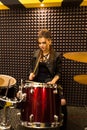 Young beautiful tattooed girl in a leather jacket plays drums in a recording Studio on the bright black and yellow band