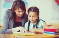 Young beautiful teacher with schoolgirl reading book in the classroom