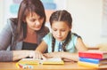 Young beautiful teacher with schoolgirl reading book in the classroom