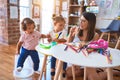 Young beautiful teacher and toddlers playing meals using plastic food and cutlery toy at kindergarten