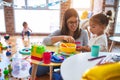 Young beautiful teacher and toddlers playing on the table with lots of toys at kindergarten Royalty Free Stock Photo