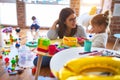 Young beautiful teacher and toddlers playing on the table with lots of toys at kindergarten Royalty Free Stock Photo