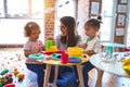 Young beautiful teacher and toddlers playing on the table with lots of toys at kindergarten Royalty Free Stock Photo