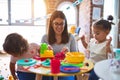 Young beautiful teacher and toddlers playing on the table with lots of toys at kindergarten Royalty Free Stock Photo