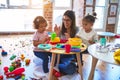 Young beautiful teacher and toddlers playing on the table with lots of toys at kindergarten Royalty Free Stock Photo