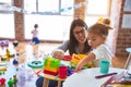 Young beautiful teacher and toddlers playing on the table with lots of toys at kindergarten Royalty Free Stock Photo