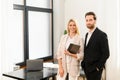 Young beautiful team of man and woman is using digital tablet while standing at the office. They holding tablet in hands