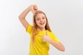 Young beautiful teen girl with blonde hair wearing casual yellow t shirt, stands over white studio background, smiling making Royalty Free Stock Photo