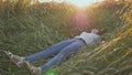 A young beautiful teen girl falls into a wheat field on a soft sunset.