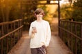 Young beautiful teen girl in headphones listening to music in phone while walk by street at autumn Royalty Free Stock Photo