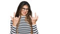 Young beautiful teen girl wearing casual clothes and glasses shouting with crazy expression doing rock symbol with hands up Royalty Free Stock Photo
