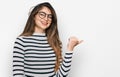 Young beautiful teen girl wearing casual clothes and glasses smiling with happy face looking and pointing to the side with thumb Royalty Free Stock Photo