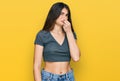 Young beautiful teen girl wearing casual crop top t shirt smelling something stinky and disgusting, intolerable smell, holding Royalty Free Stock Photo