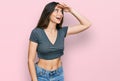 Young beautiful teen girl wearing casual crop top t shirt very happy and smiling looking far away with hand over head Royalty Free Stock Photo