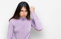 Young beautiful teen girl wearing turtleneck sweater angry and mad raising fist frustrated and furious while shouting with anger Royalty Free Stock Photo