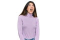 Young beautiful teen girl wearing turtleneck sweater angry and mad screaming frustrated and furious, shouting with anger Royalty Free Stock Photo