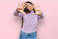 Young beautiful teen girl wearing turtleneck sweater doing frame using hands palms and fingers, camera perspective Royalty Free Stock Photo