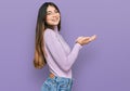 Young beautiful teen girl wearing turtleneck sweater pointing aside with hands open palms showing copy space, presenting Royalty Free Stock Photo