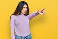 Young beautiful teen girl wearing turtleneck sweater pointing with finger surprised ahead, open mouth amazed expression, something Royalty Free Stock Photo