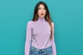 Young beautiful teen girl wearing turtleneck sweater in shock face, looking skeptical and sarcastic, surprised with open mouth Royalty Free Stock Photo