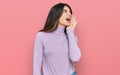 Young beautiful teen girl wearing turtleneck sweater shouting and screaming loud to side with hand on mouth Royalty Free Stock Photo