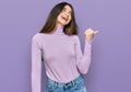 Young beautiful teen girl wearing turtleneck sweater smiling with happy face looking and pointing to the side with thumb up Royalty Free Stock Photo