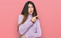 Young beautiful teen girl wearing turtleneck sweater surprised pointing with finger to the side, open mouth amazed expression Royalty Free Stock Photo