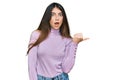 Young beautiful teen girl wearing turtleneck sweater surprised pointing with hand finger to the side, open mouth amazed expression Royalty Free Stock Photo