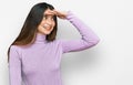 Young beautiful teen girl wearing turtleneck sweater very happy and smiling looking far away with hand over head Royalty Free Stock Photo