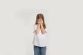 a young beautiful teenage girl is crying with her hands covering her face on a white isolated background. Royalty Free Stock Photo