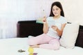 Young beautiful teenage girl sitting on sofa with pencil and paper, counting before putting coins in piggy Bank