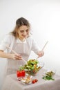 young beautiful teenage girl stirs diligently salad she leaned over bowl little smiling green lettuce leaves tablecloth Royalty Free Stock Photo