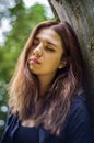 Young beautiful teenager girl with long hair in a shirt and denim shorts resting on a tree during a walk in the park Striysky in Royalty Free Stock Photo