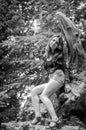 Young beautiful teenager girl with long hair in a shirt and denim shorts resting on a tree during a walk in the park Striysky in Royalty Free Stock Photo