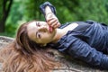 Young beautiful teenager girl with long hair in a shirt and denim shorts resting on a tree during a walk in the park Striysky in Royalty Free Stock Photo