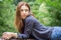 Young beautiful teenager girl with long hair in a shirt and denim shorts resting on a tree during a walk in the park Striysky in Royalty Free Stock Photo