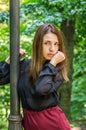 Young beautiful teenager girl with long hair walking in Striysky park in Lviv, posing near a lamp to illuminate the bushes and Royalty Free Stock Photo
