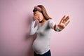 Young beautiful teenager girl pregnant expecting baby over isolated pink background covering eyes with hands and doing stop Royalty Free Stock Photo