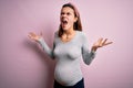 Young beautiful teenager girl pregnant expecting baby over isolated pink background crazy and mad shouting and yelling with Royalty Free Stock Photo