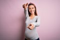 Young beautiful teenager girl pregnant expecting baby over isolated pink background pointing to you and the camera with fingers, Royalty Free Stock Photo