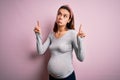 Young beautiful teenager girl pregnant expecting baby over isolated pink background Pointing up looking sad and upset, indicating Royalty Free Stock Photo