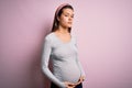 Young beautiful teenager girl pregnant expecting baby over isolated pink background Relaxed with serious expression on face Royalty Free Stock Photo