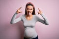 Young beautiful teenager girl pregnant expecting baby over isolated pink background shouting with crazy expression doing rock Royalty Free Stock Photo