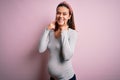 Young beautiful teenager girl pregnant expecting baby over isolated pink background Smiling with open mouth, fingers pointing and Royalty Free Stock Photo