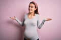 Young beautiful teenager girl pregnant expecting baby over isolated pink background smiling showing both hands open palms, Royalty Free Stock Photo