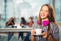 Young beautiful teenager girl sitting in cafe with a white cup, Royalty Free Stock Photo