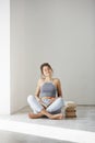 Young beautiful tender girl smiling with closed eyes holding book sitting on floor over white wall early in morning. Royalty Free Stock Photo